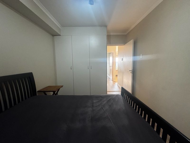 A functional bedroom featuring built-in wardrobes and neutral wall finishes, providing a clean and practical living space.