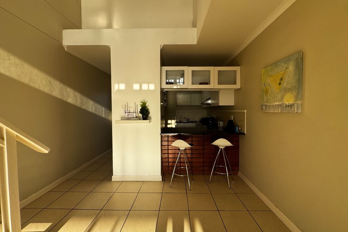 A compact kitchen area featuring built-in cabinetry, a breakfast bar, and tiled flooring, offering a functional space for meal preparation.