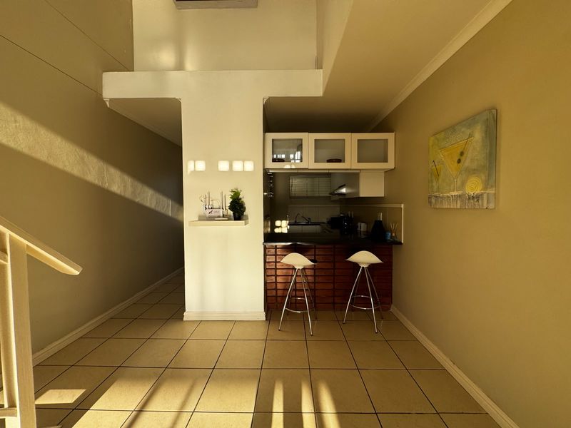 A compact kitchen area featuring built-in cabinetry, a breakfast bar, and tiled flooring, offering a functional space for meal preparation.