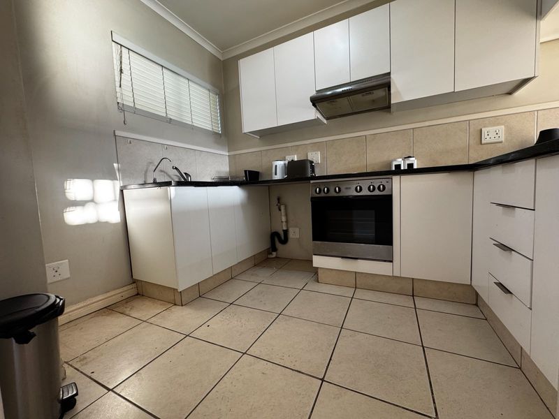 A functional kitchen featuring white cabinetry, a built-in oven with extractor fan, tiled backsplash, and tiled flooring.