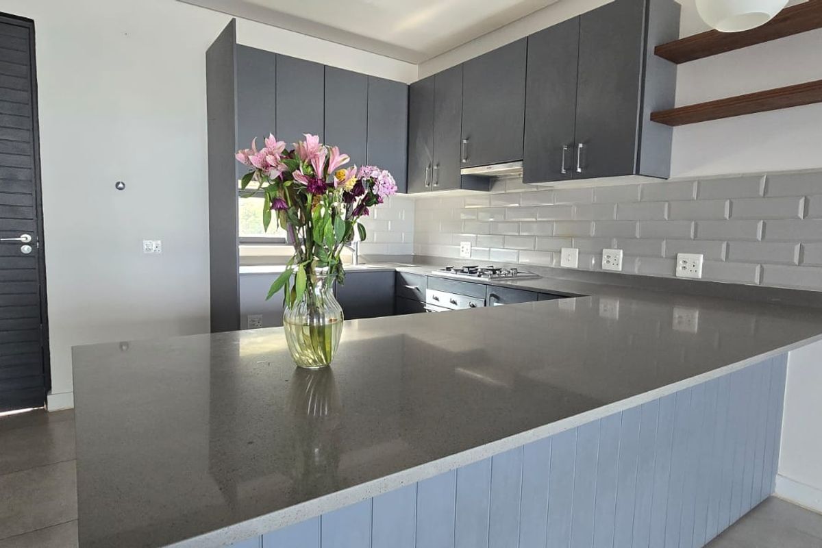 Modern kitchen featuring grey cabinetry, quartz countertops, subway tile backsplash, built-in gas hob, oven, and floating timber shelving.