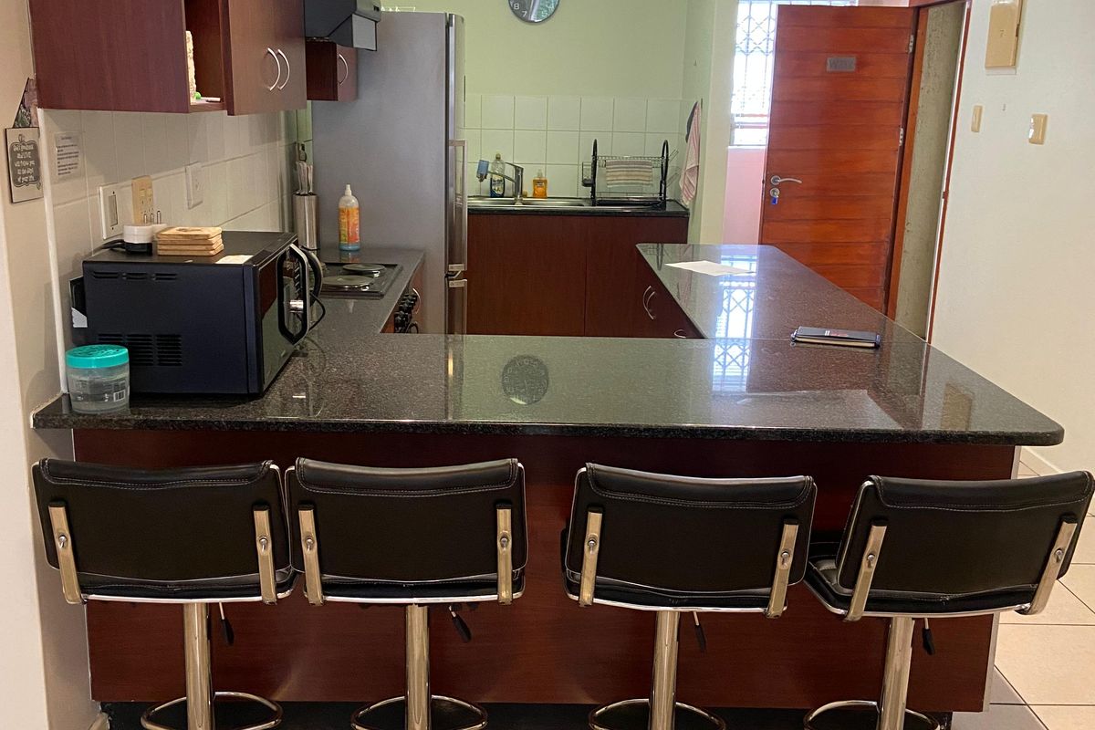 A functional kitchen featuring dark wood cabinetry, granite countertops, a breakfast bar, and tiled flooring, providing a practical layout for daily use.