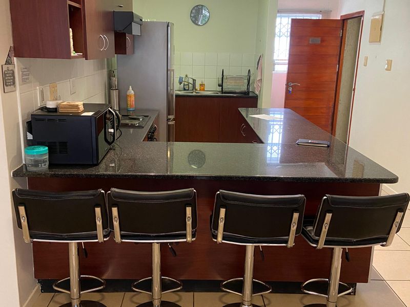 A functional kitchen featuring dark wood cabinetry, granite countertops, a breakfast bar, and tiled flooring, providing a practical layout for daily use.