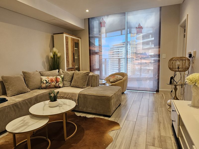A well-maintained living room featuring wood-look tile flooring, recessed lighting, and a large window with a view, providing a bright and comfortable living space.