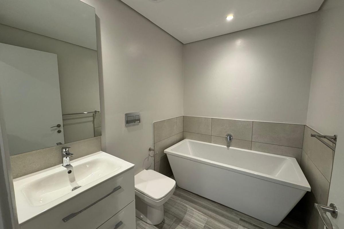 Modern bathroom featuring a sleek freestanding bathtub, wall-hung toilet, vanity with basin, and neutral tile finishes.