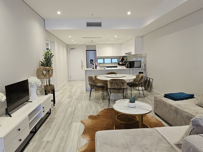 Modern open-plan living and dining area featuring tiled flooring, recessed lighting, and a functional kitchen with integrated cabinetry and island.