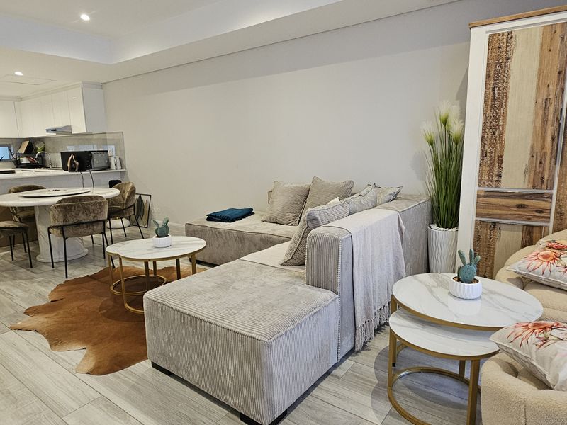 Modern open-plan living area featuring tiled flooring, recessed lighting, ducted air conditioning, and a sleek kitchen with stone benchtops.