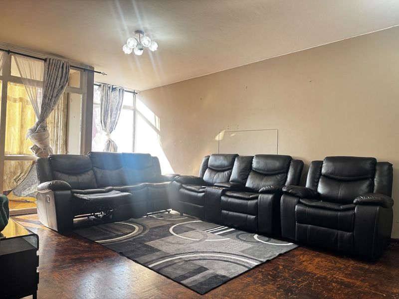 A living room featuring parquet flooring and a large glass sliding door leading to an outdoor area, providing natural light.