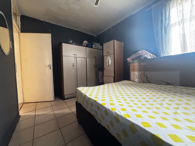 Bedroom featuring tiled flooring and built-in cupboards, showing signs of ceiling water damage and requiring cosmetic updates.