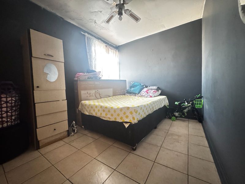 A bedroom featuring tiled flooring and a ceiling fan, currently requiring maintenance to the ceiling finish.