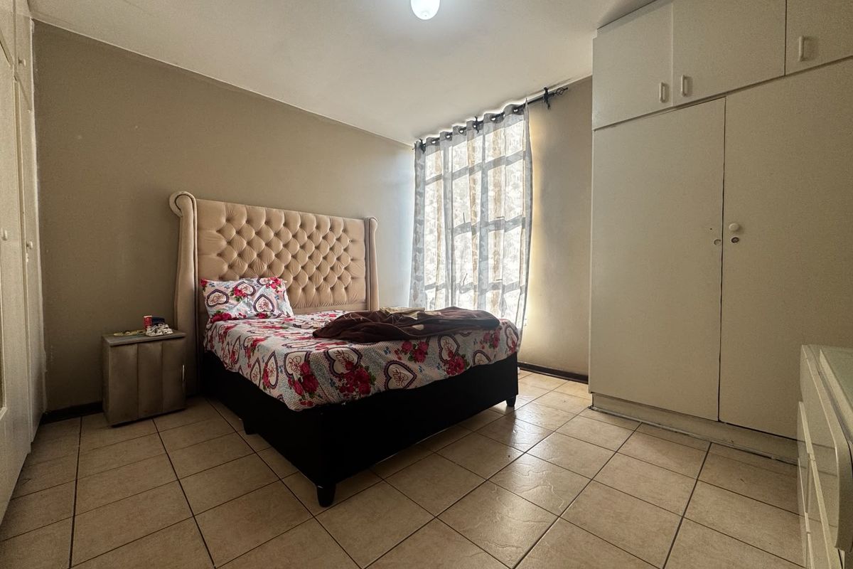 A bedroom featuring tiled flooring and built-in cupboards, providing functional storage space within the apartment.