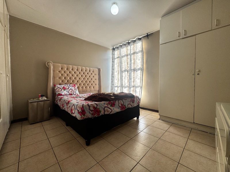 A bedroom featuring tiled flooring and built-in cupboards, providing functional storage space within the apartment.