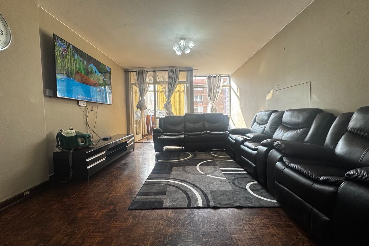 Spacious living room featuring traditional parquet flooring and direct access to a balcony through sliding glass doors.