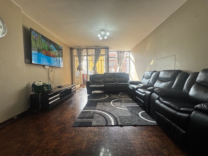 Spacious living room featuring traditional parquet flooring and direct access to a balcony through sliding glass doors.