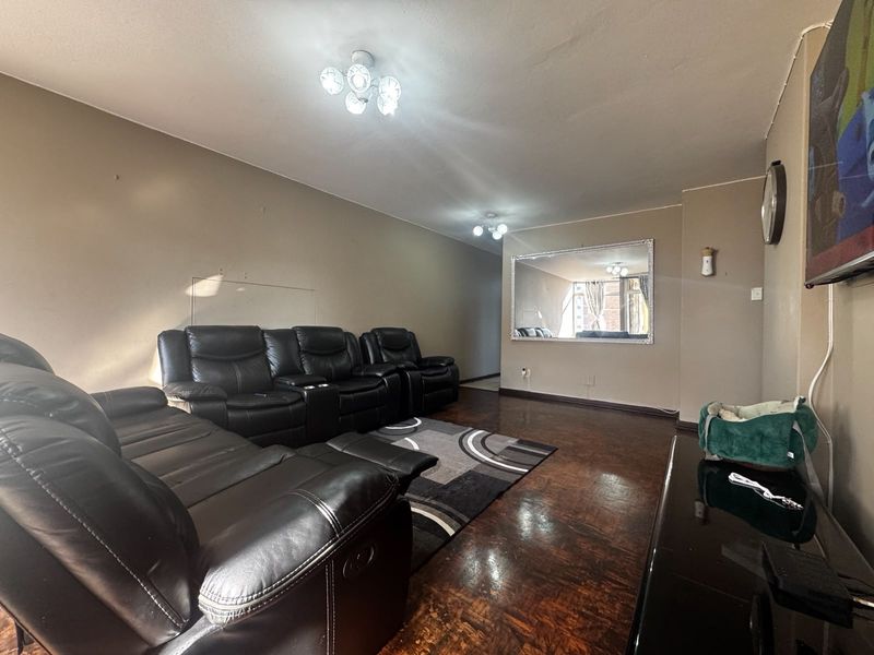 A living room featuring dark parquet flooring, neutral wall tones, and multiple ceiling light fixtures, providing a functional space for relaxation.
