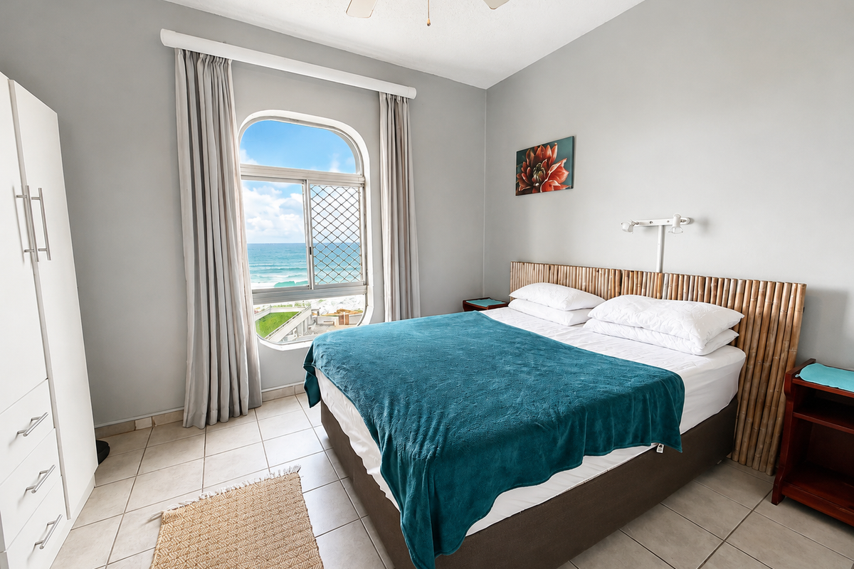 A bedroom featuring tiled flooring, a ceiling fan, and an arched window offering ocean views.