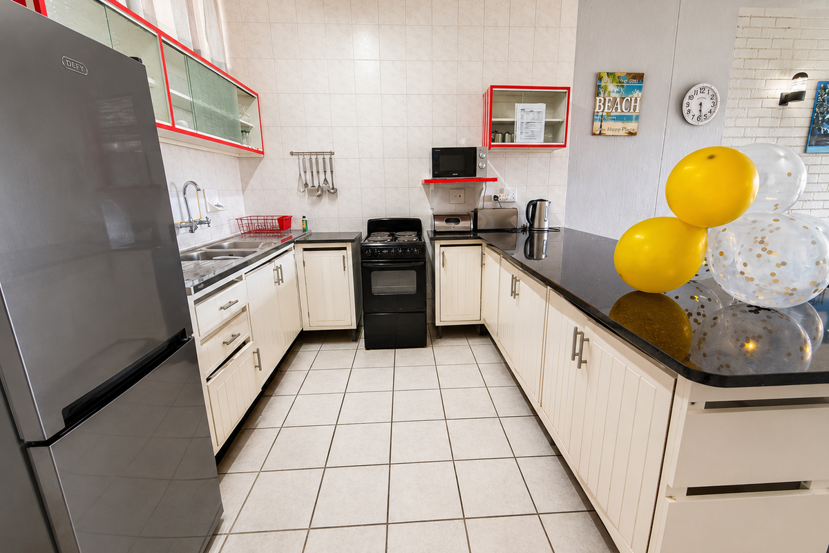 A functional kitchen featuring white cabinetry, dark granite countertops, tiled flooring, and a tiled backsplash, providing a clean and practical workspace.