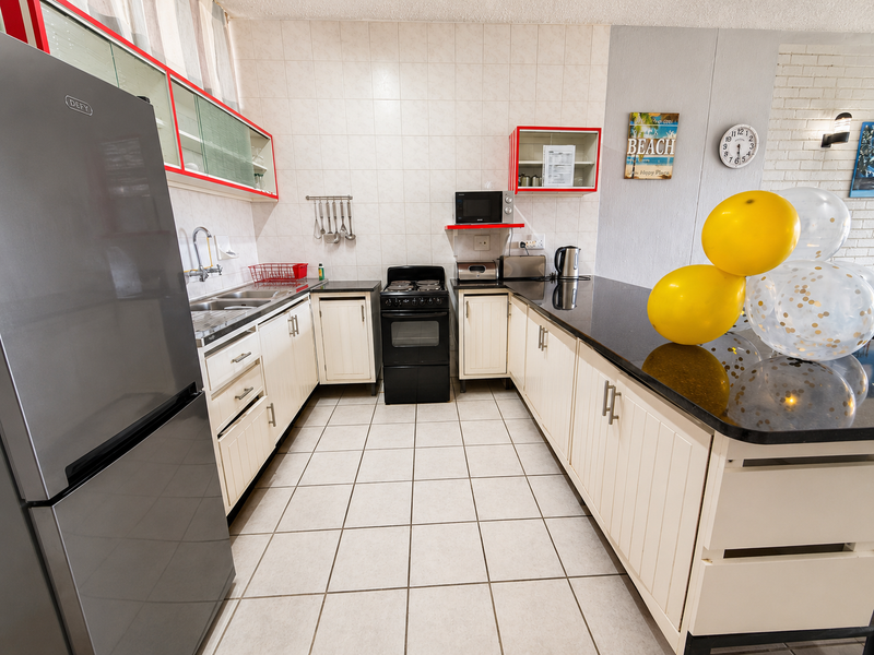 A functional kitchen featuring white cabinetry, dark granite countertops, tiled flooring, and a tiled backsplash, providing a clean and practical workspace.