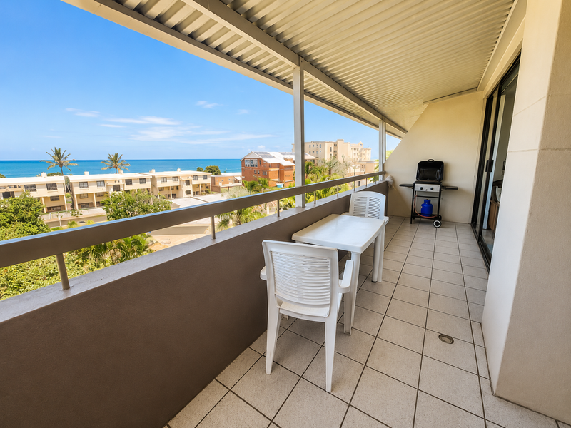 A spacious covered balcony featuring tiled flooring, a metal balustrade, and expansive ocean views, providing an ideal outdoor living space.