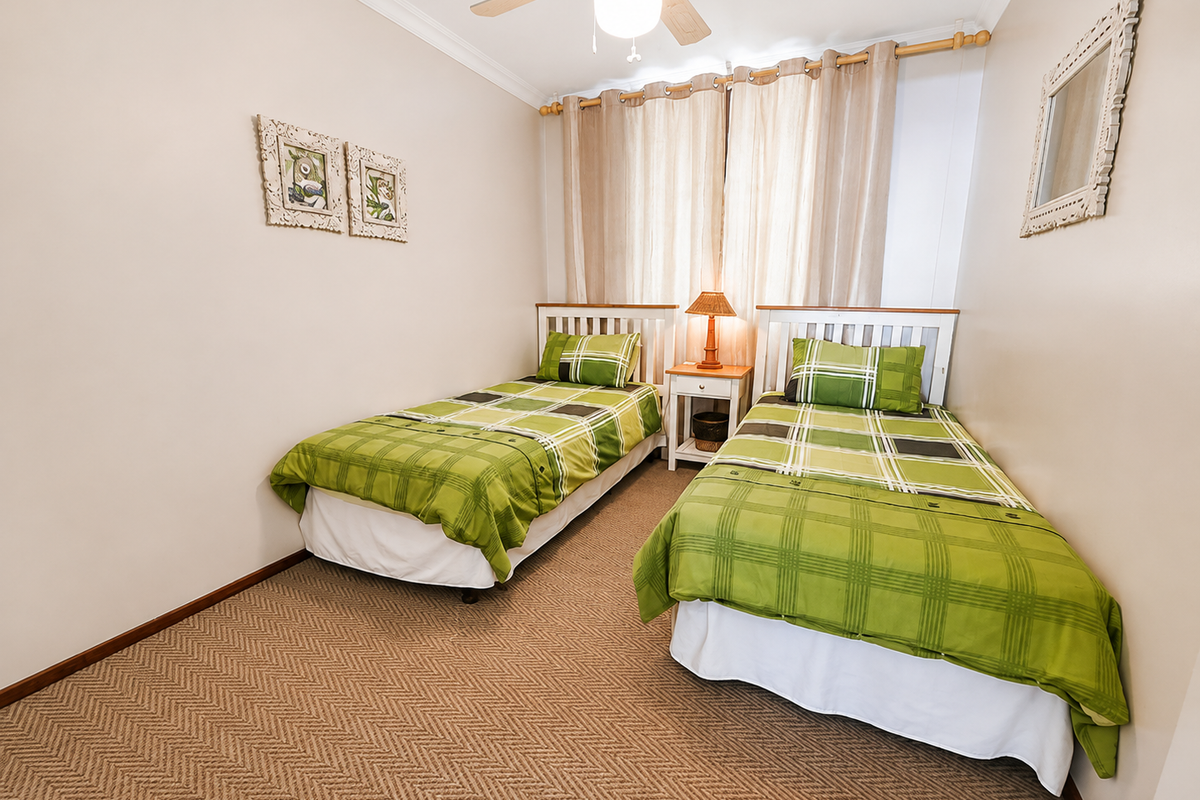 A bedroom featuring neutral walls, carpeted flooring, and a ceiling fan, providing a functional space for rest.