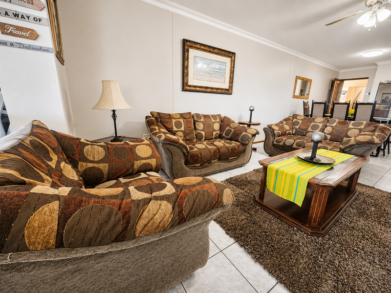Spacious living room featuring tiled flooring, coved cornicing, and a ceiling fan, providing a comfortable and functional area for relaxation.