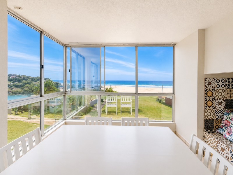 Enclosed balcony featuring expansive ocean views, large sliding glass windows, and a decorative tiled built-in seating area.