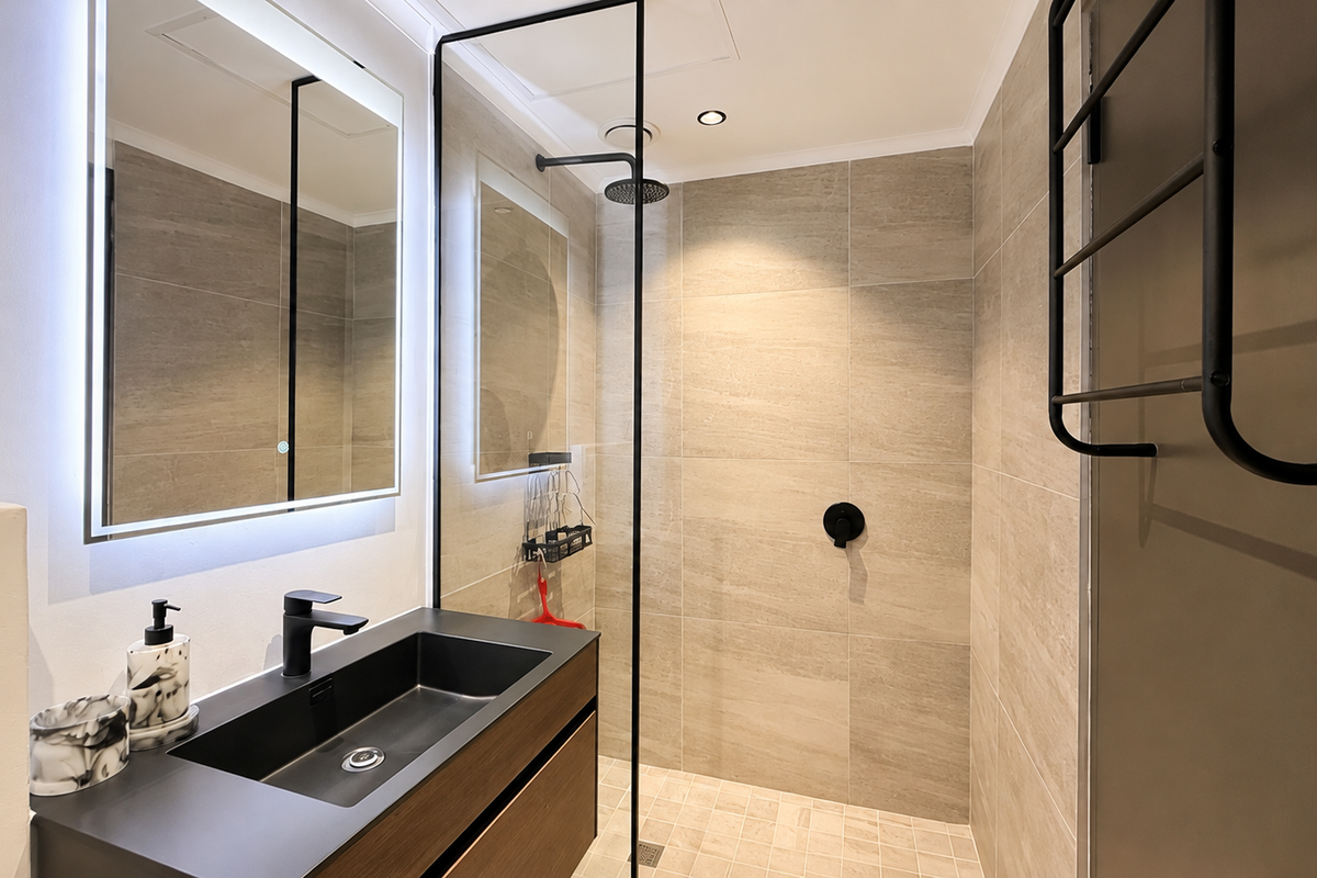 Modern bathroom featuring a walk-in shower with black frame, wall-mounted vanity with integrated basin, LED backlit mirror, and a heated towel rail.