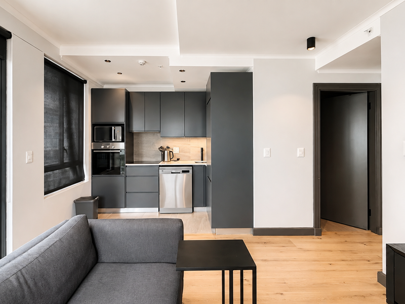 Modern open-plan living area featuring a sleek kitchen with integrated appliances, timber flooring, and neutral finishes throughout.