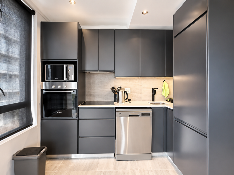 Modern kitchen featuring matte grey cabinetry, integrated appliances, stone countertops, and recessed lighting, offering a sleek and functional culinary space.