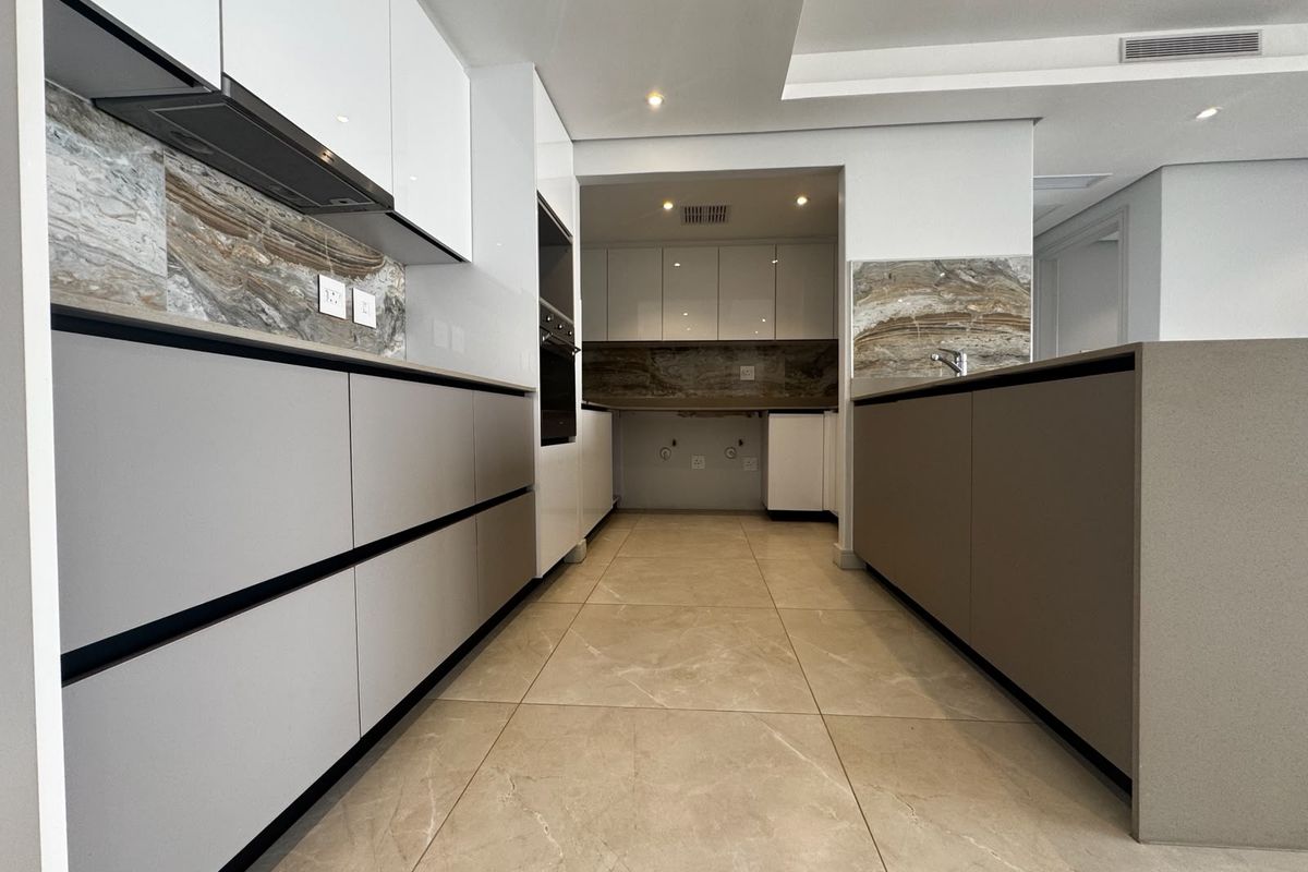 Modern kitchen featuring sleek handleless cabinetry, stone splashbacks, integrated appliances, and high-quality tiled flooring in a clean, contemporary layout.