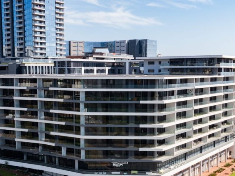 Aerial view of a modern multi-story apartment complex featuring extensive glass facades and private balconies.