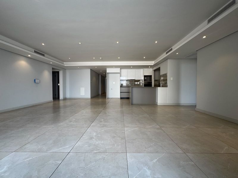 Spacious open-plan living area featuring large-format porcelain tiles, recessed lighting, ducted air conditioning, and a modern kitchen with integrated appliances.