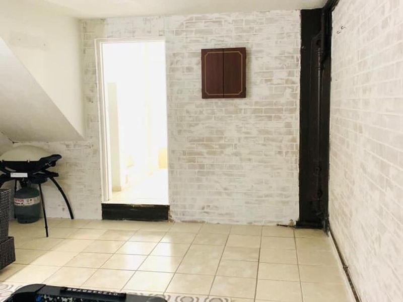 Utility space featuring tiled flooring, exposed plumbing, and a built-in wall cabinet, offering potential for renovation or improved storage configuration.
