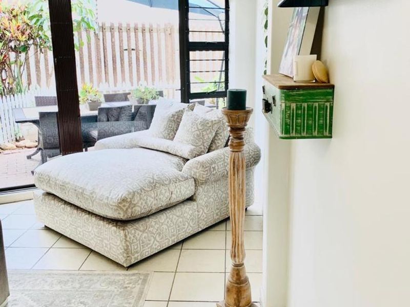 A bright living area featuring tiled flooring and large sliding glass doors that provide seamless access to the outdoor patio space.