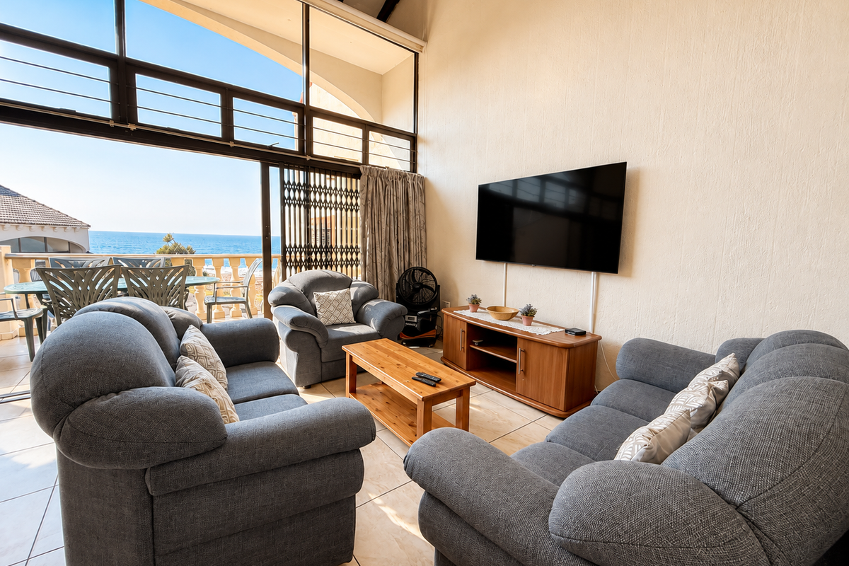 Spacious living room featuring high vaulted ceilings, large windows with ocean views, and direct access to a private balcony.