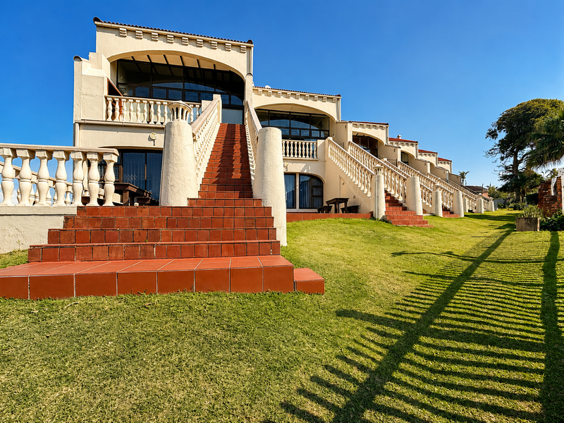Rear view of a multi-level apartment complex featuring terracotta tiled staircases, classic balustrade railings, and direct access to a well-maintained lawn area.