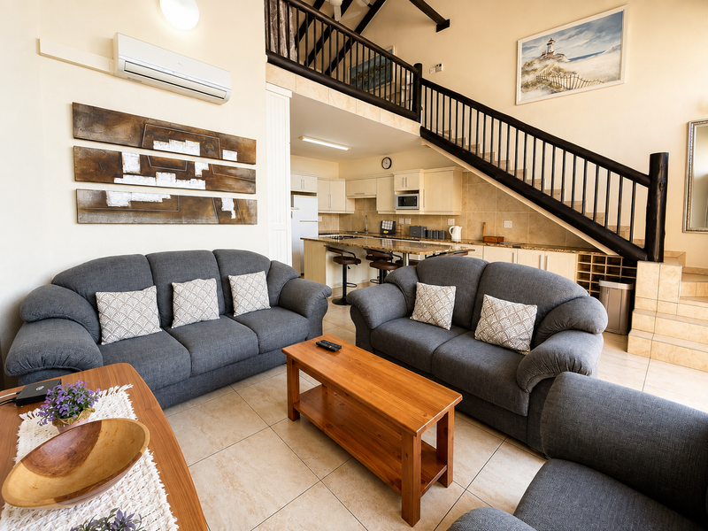 Spacious open-plan living area featuring a modern kitchen with granite countertops, tiled flooring, and a mezzanine level accessed by a timber staircase.