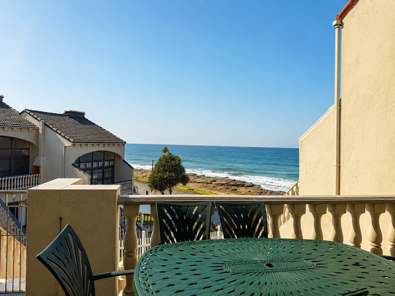 A balcony featuring a classic balustrade railing with direct views of the ocean and coastline.