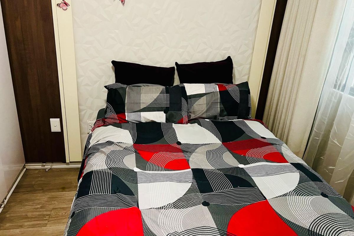 A cozy bedroom featuring laminate flooring, a textured feature wall, and a built-in wardrobe, providing a functional and comfortable sleeping space.