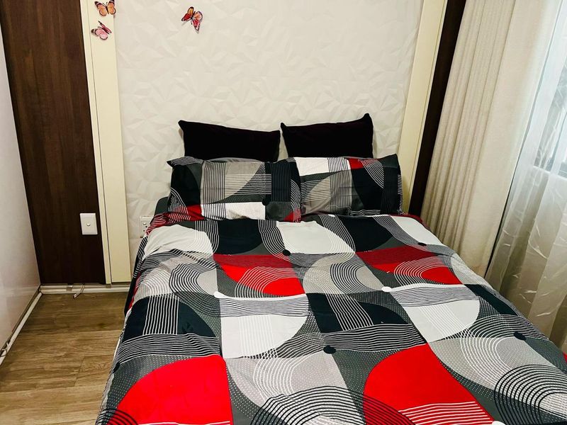 A cozy bedroom featuring laminate flooring, a textured feature wall, and a built-in wardrobe, providing a functional and comfortable sleeping space.