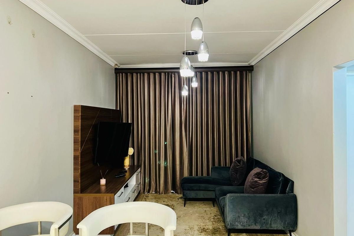 A well-maintained living room featuring crown molding, modern pendant lighting, and a built-in media unit, creating a cozy and functional space.