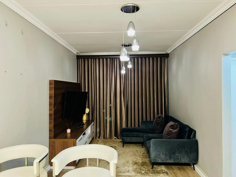 A well-maintained living room featuring crown molding, modern pendant lighting, and a built-in media unit, creating a cozy and functional space.