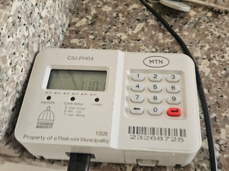A wall-mounted prepaid electricity meter unit installed on a granite countertop surface.
