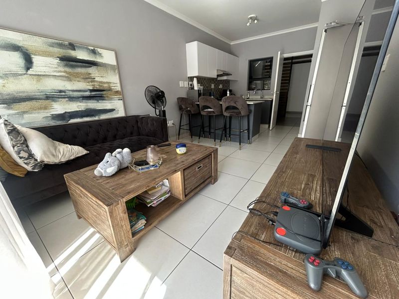 Open-plan living area featuring a modern kitchen with island seating, tiled flooring, and neutral wall finishes.
