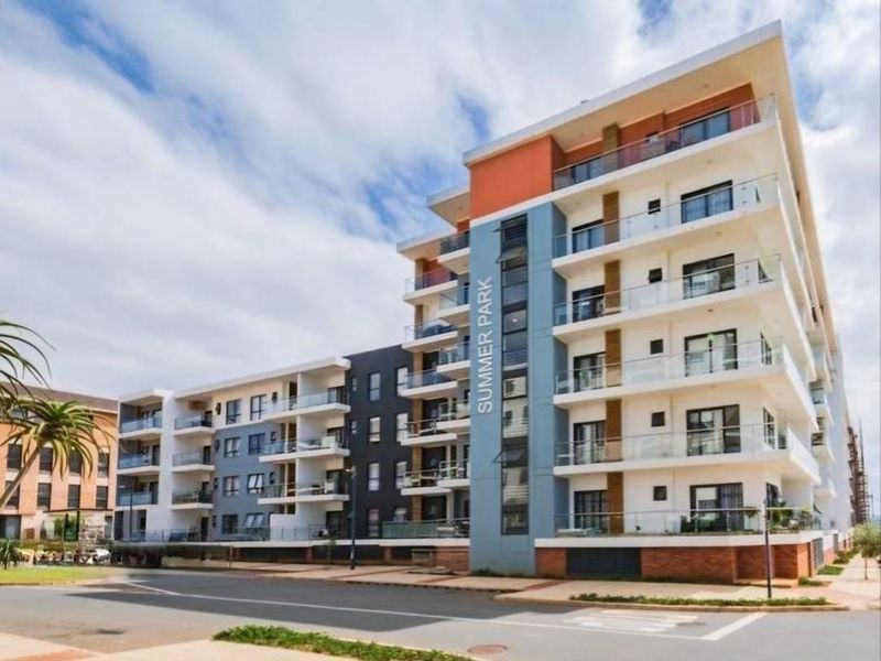 A modern multi-story apartment building featuring contemporary architectural design, private balconies with glass balustrades, and a prominent street-facing facade.