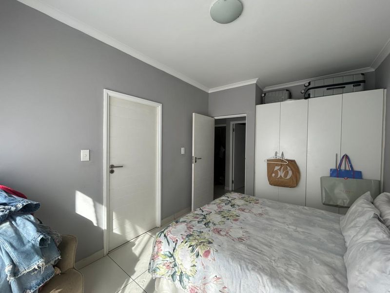 A well-maintained bedroom featuring neutral grey walls, tiled flooring, and ample built-in cupboard storage space.