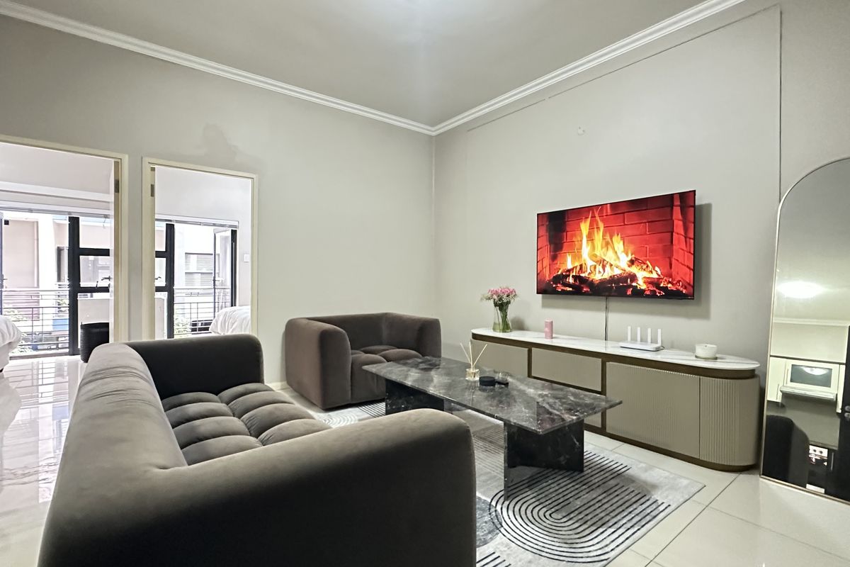 A well-maintained living room featuring neutral walls, tiled flooring, and decorative cornice detailing, providing a clean and contemporary living space.