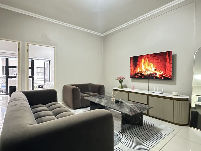 A well-maintained living room featuring neutral walls, tiled flooring, and decorative cornice detailing, providing a clean and contemporary living space.