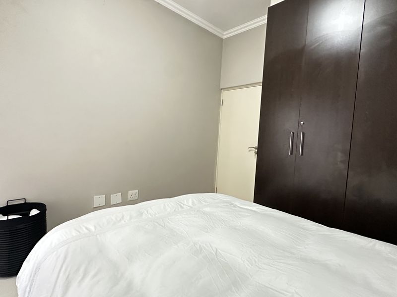 A bedroom featuring a large dark wood built-in wardrobe and neutral wall finishes.