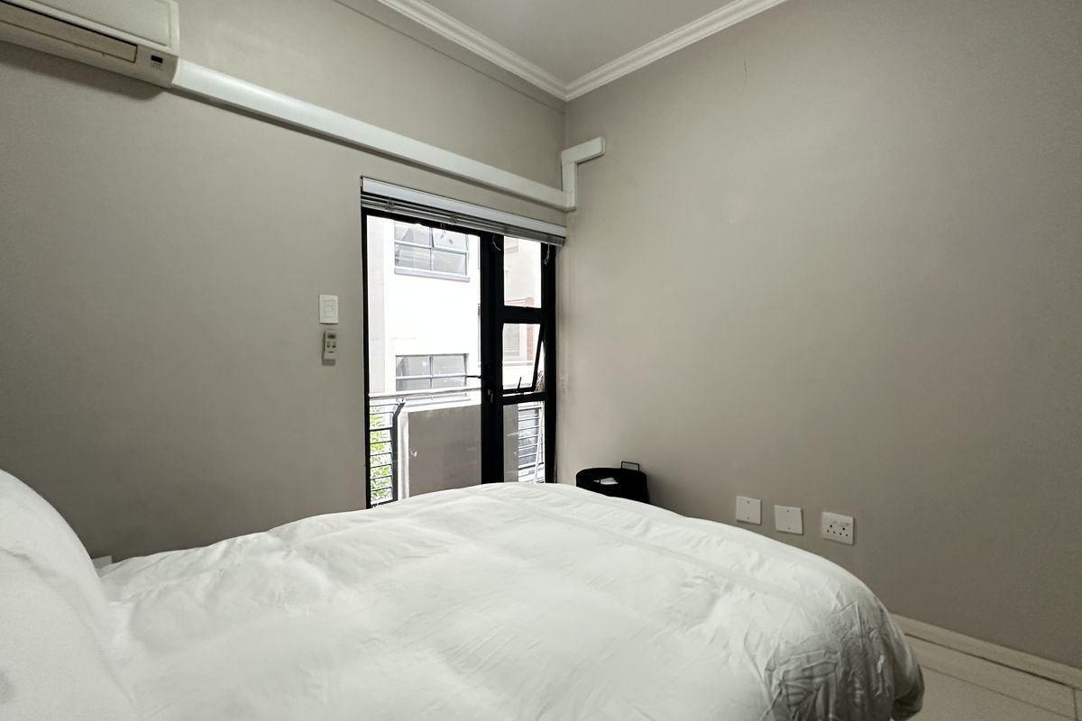 A bedroom featuring neutral walls, coving, a split-system air conditioner, and a sliding glass door providing natural light.